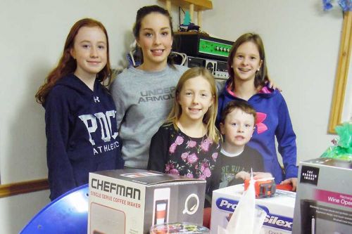 Rachel, Myh, Maddison, (back row) and Anna and Cooper (front row), pose in front of some of the items that were auctioned off at the Snow Road Snowmobile Club's dinner and Chinese auction fundraiser on January 16.